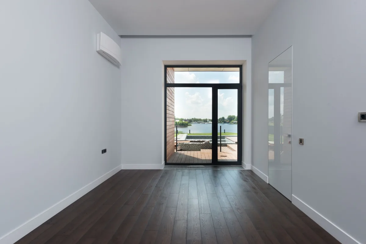 Living room viewed through a glass door toward a lakeside terrace.