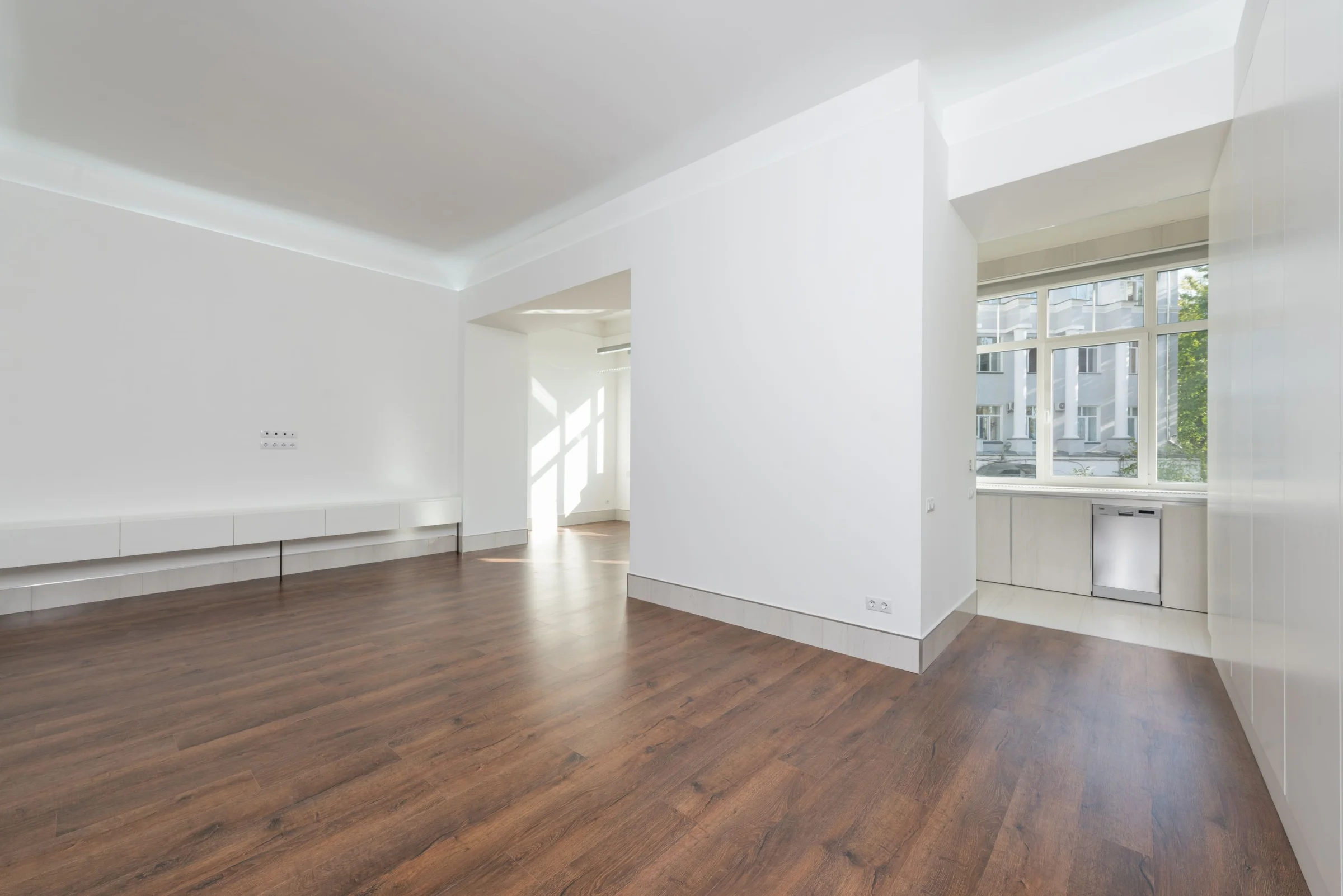 Bright apartment interior with oak flooring and tall windows.